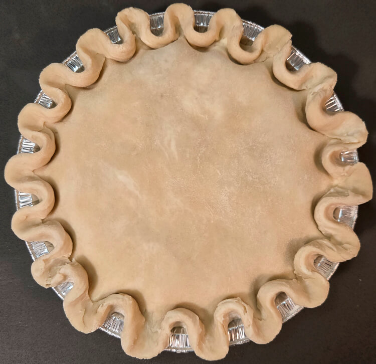 overhead photo of a sealed double crusted pie with crimped edges