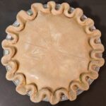 an overhead photo of a turkey pot pie with slashing in the shape of a snowflake before baking