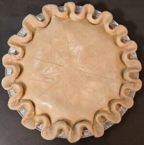 an overhead photo of a turkey pot pie with slashing in the shape of a snowflake before baking