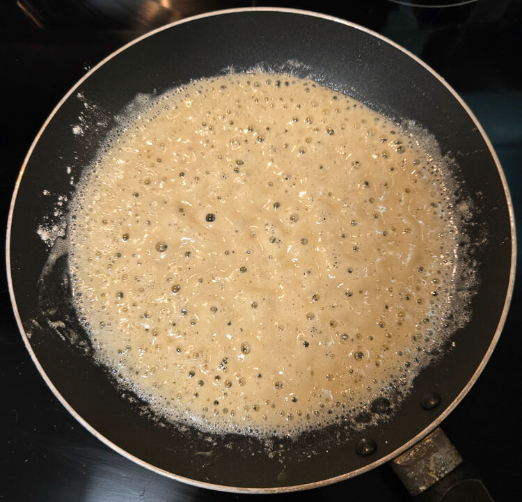 overhead photo of a roux just beginning to cook before it turns golden brown after butter and flour have been whisked together in a nonstick pan