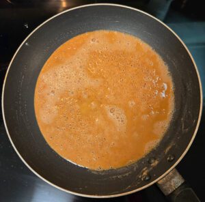 an overhead photo of a golden brown roux in a nonstick pan
