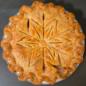 an overhead photo of a baked turkey pot pie with slashes cut out in the crust in the shape of a snowflake