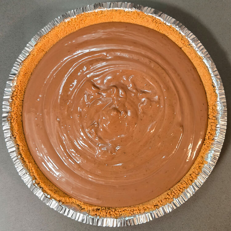 overhead photo of a freshly filled chocolate cream pie in a graham cracker crust with chocolate pudding