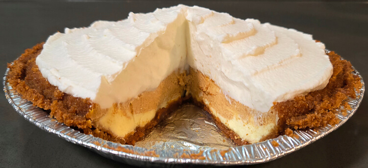 a cross section of a swirled pumpkin cheesecake pie topped with whipped cream