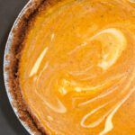 an overhead photo of a swirled pumpkin cheesecake pie in a graham cracker crust