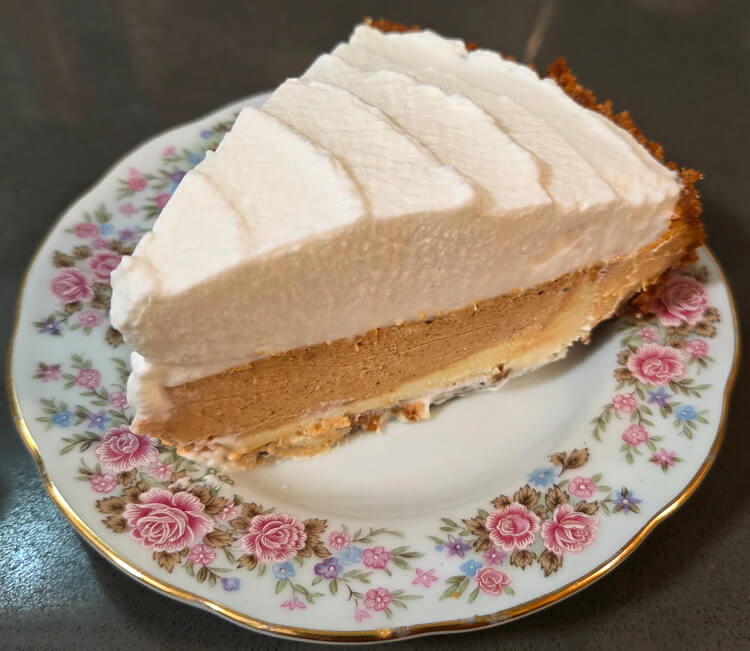 a photograph of a slice of pumpkin cheesecake on a floral plate topped with whipped cream