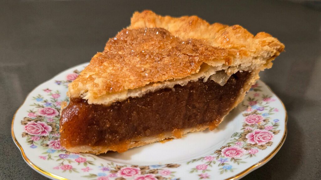 a close up photograph of a slice of rich, gooey, Amish apple Schnitz pie on an antique floral plate