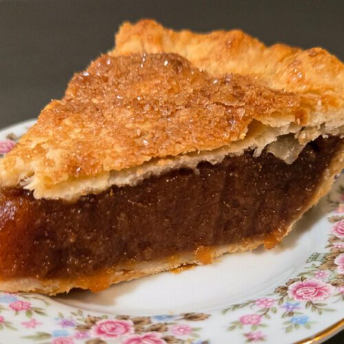 a close up photograph of a slice of rich, gooey, Amish apple Schnitz pie on an antique floral plate