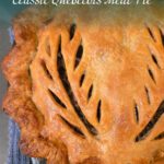 Close-up of a golden Québécois tourtière with hand-cut leaf vents and crimped edges, baked in a cast iron skillet.