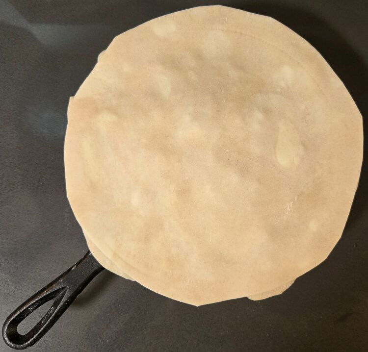 overhead photo of assembling a double crust pie in a cast iron pan