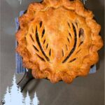 Golden-brown French-Canadian tourtière baked in a cast-iron skillet with decorative steam vents, labeled as a Christmas meat pie recipe.