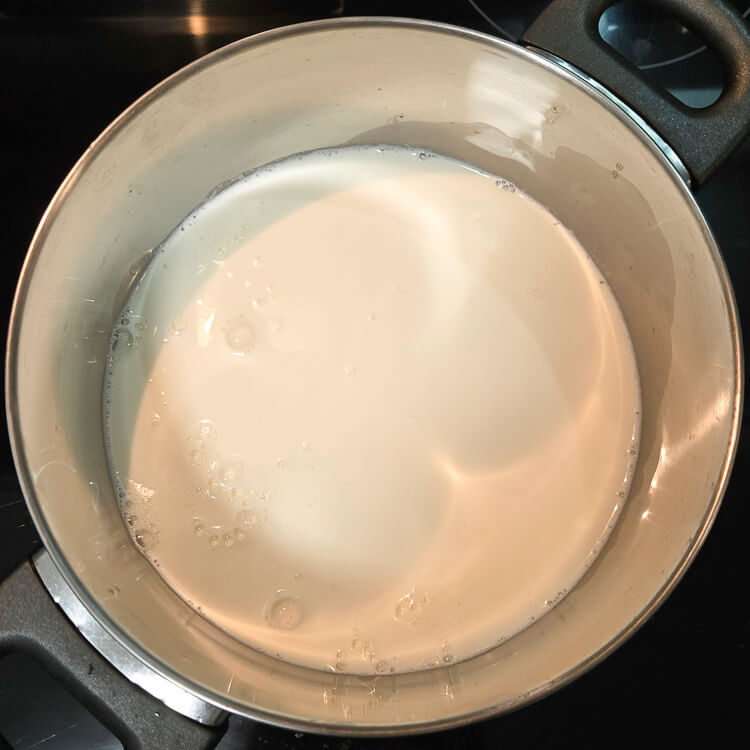 an overhead photo of scalding milk and cream in a pot on a stove