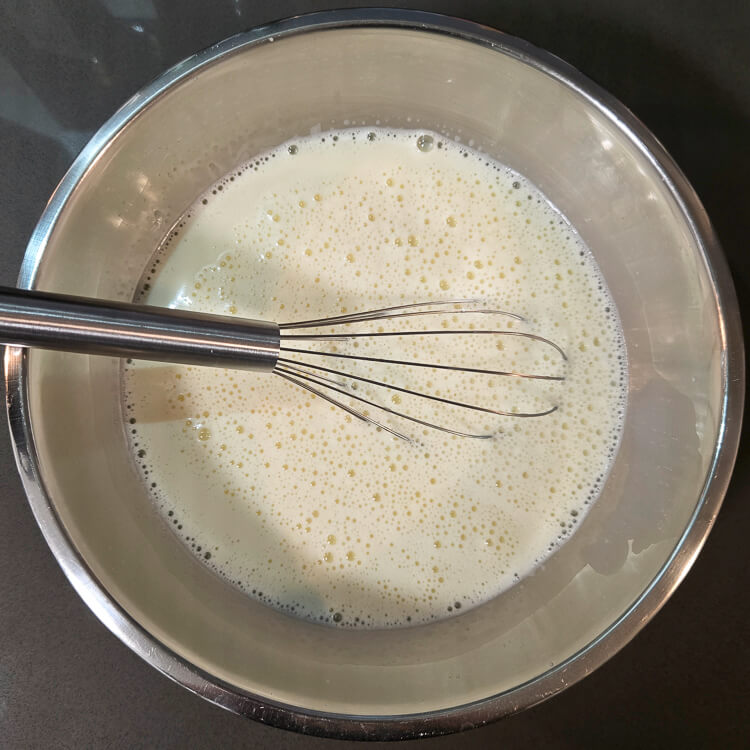 an overhead photo of homemade vanilla pudding base in a mixing bowl before being cooked on the stovetop