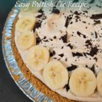 Close-up of a classic British banoffee pie topped with whipped cream, sliced bananas, and chocolate shavings in a crumb crust.