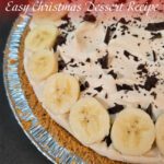 Close-up of banoffee pie with whipped cream, caramel, and banana slices in a crumb crust.