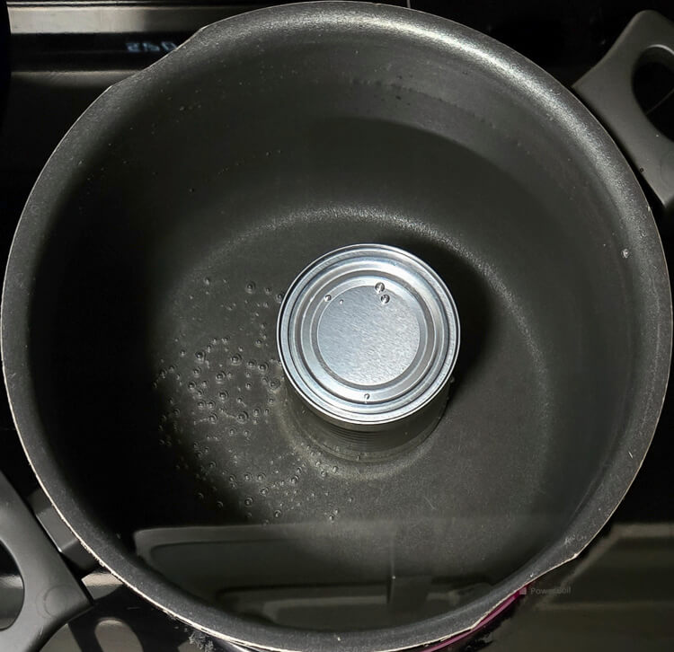 a can of condensed milk being boiled in a pot of water to make dulce de leche