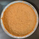 overhead photo of a baked, golden brown crumb pie crust made with digestive biscuits
