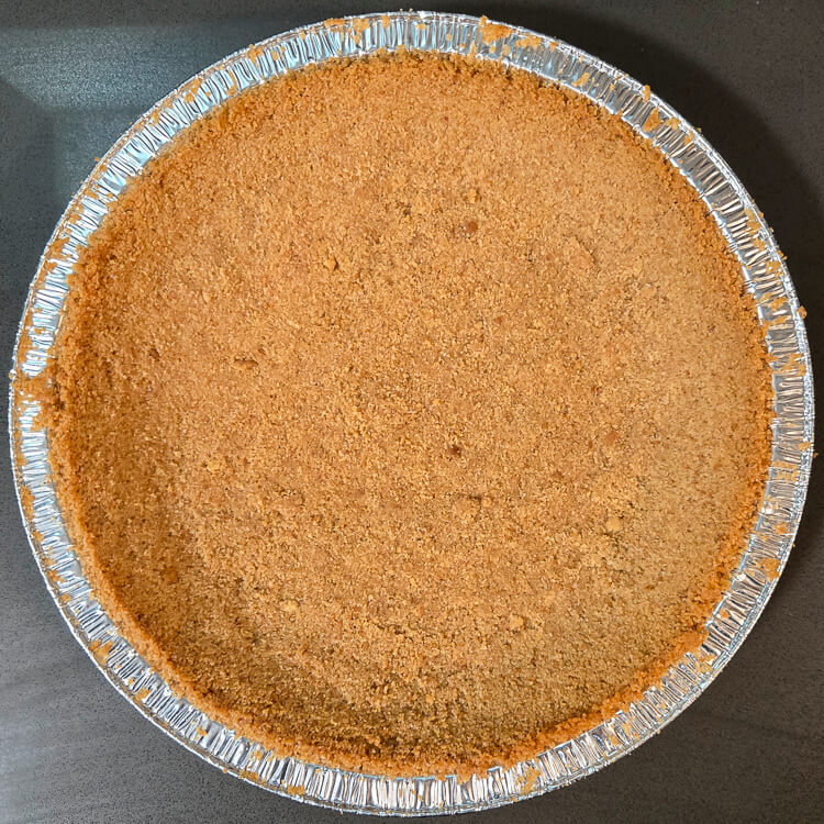 overhead photo of a baked, golden brown crumb pie crust made with digestive biscuits