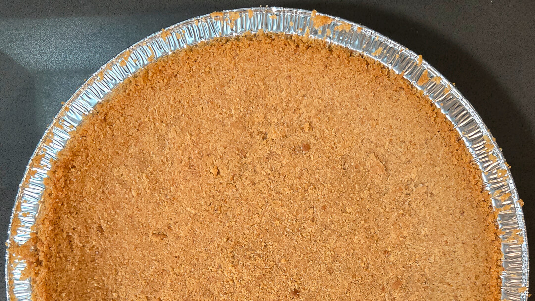 overhead photo of half of a crumb crust for a pie made with digestive biscuits as a substitute for graham crackers or as a crust for banoffee pie