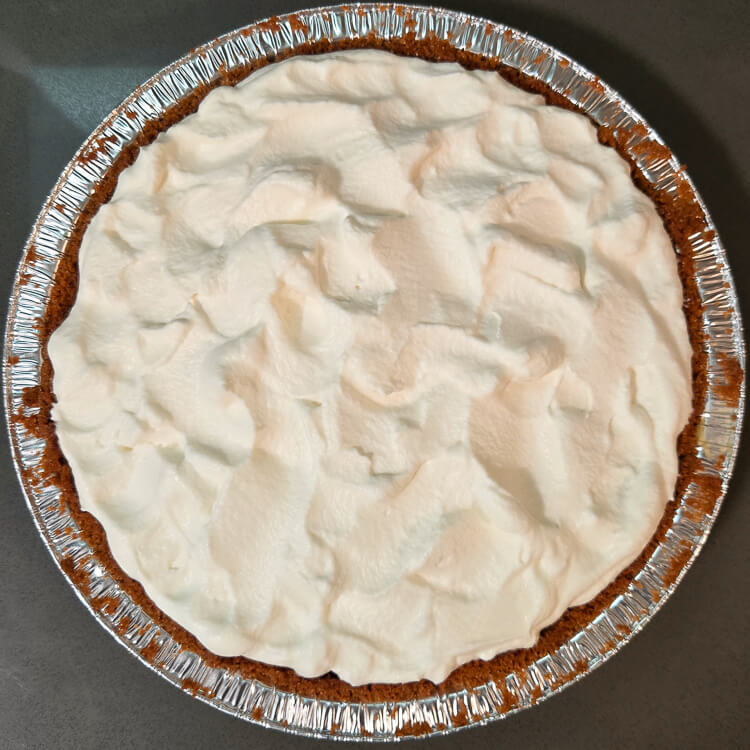 overhead photo of a cream pie in a gingersnap crust topped with fluffy whipped cream
