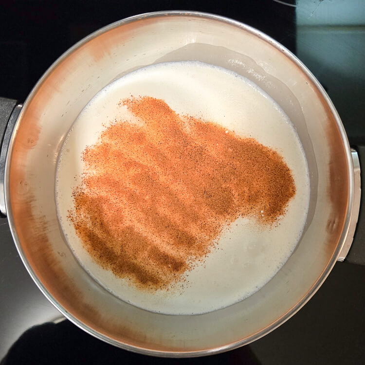 overhead photo of milk and cream in a pot with nutmeg