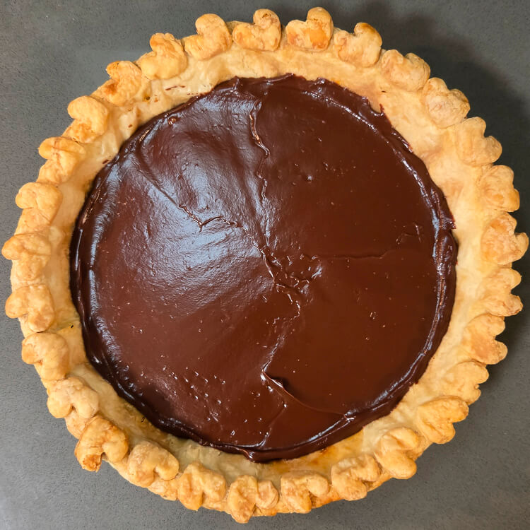 the first layer of a chocolate haupia pie: chocolate haupia poured into a golden pie crust