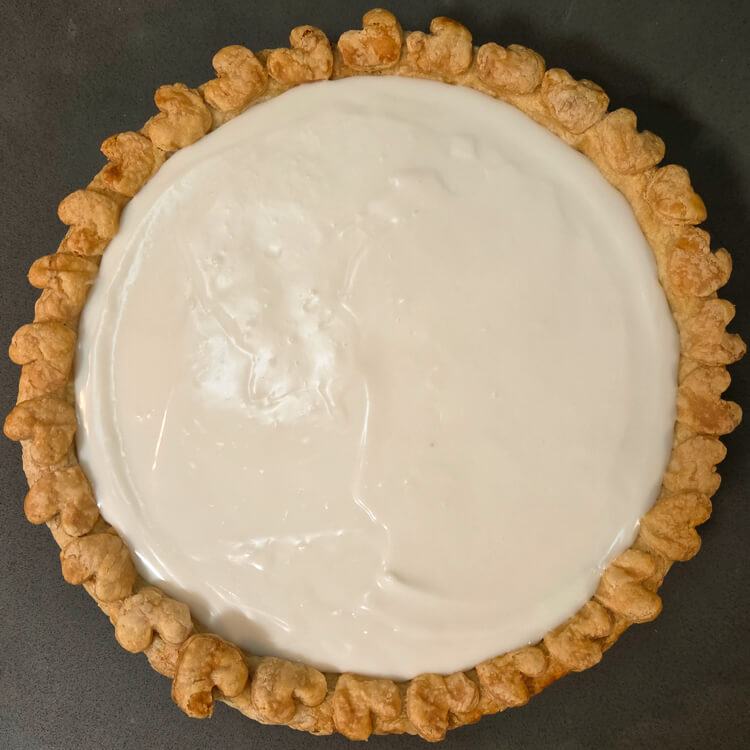 an overhead photo of a Hawaiian chocolate haupia pie before being topped with whipped cream showing coconut haupia in a golden pie crust with hearts around the edge