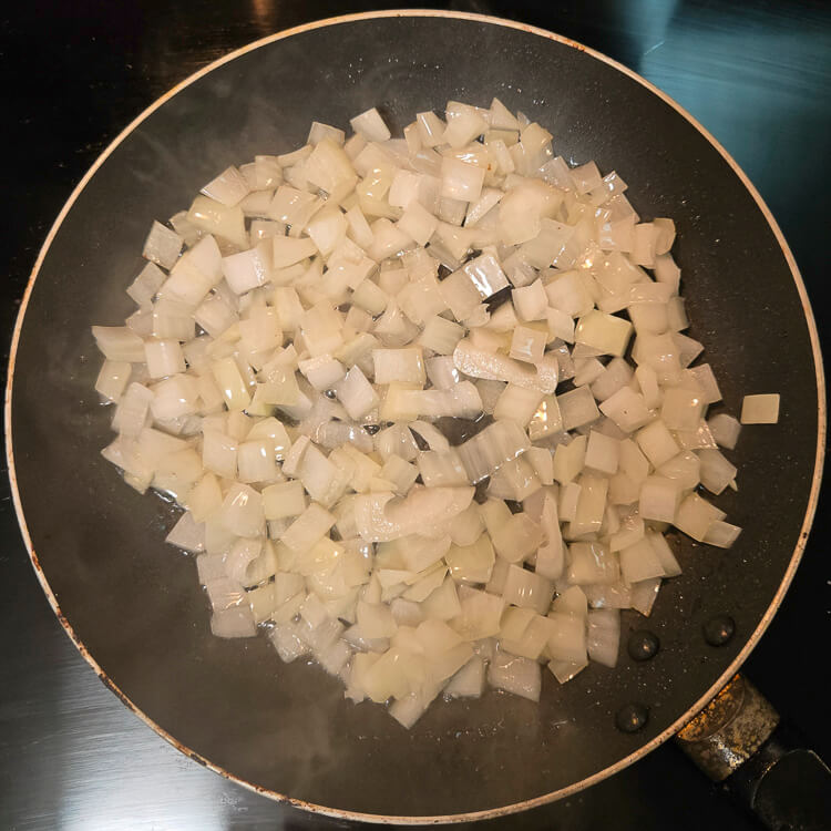overhead photo of translucent onions being sauteed in a frying pan