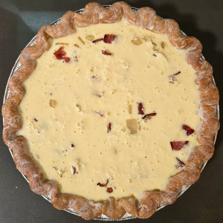 an overhead photo of an unbaked bacon and onion quiche