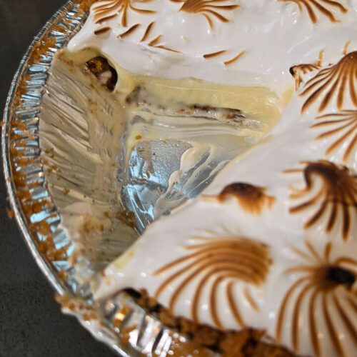 close up photo of a cross section of flapper pie with a slice cut out showing graham cracker crust, homemade old-fashioned vanilla pudding, and a meringue topping