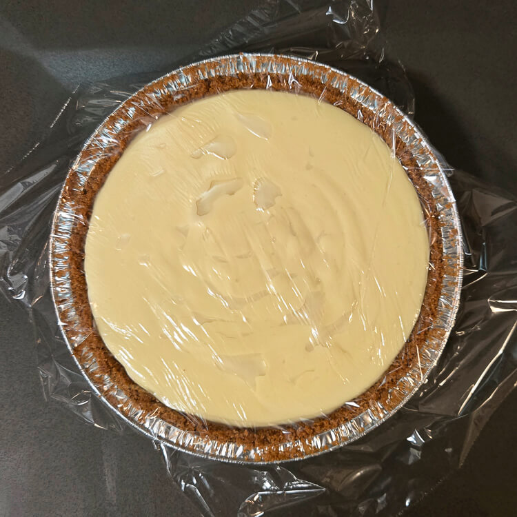 flapper pie with homemade vanilla pudding poured in before being cooled. Plastic wrap is pressed to the surface to prevent a skin from forming