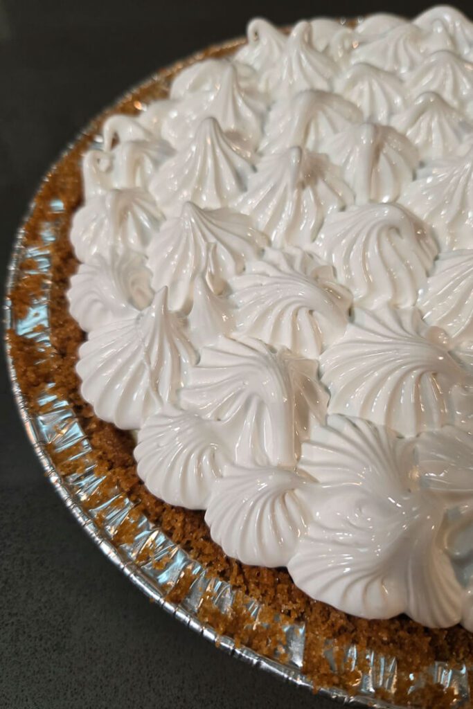 close up photo of meringue piped in swirls on top of a flapper pie before being toasted