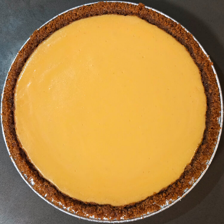 an overhead photo of a fully baked key lime pie in a graham cracker crust with no topping