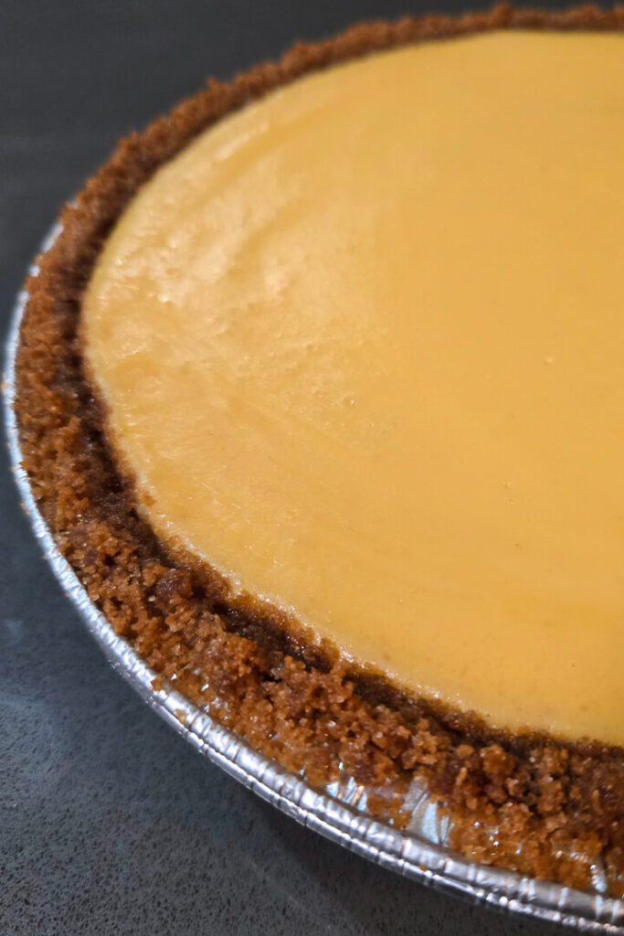a close up photo of a key lime pie with no topping in a graham cracker crust with creamy lime custard