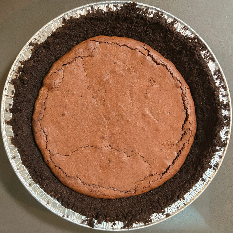 a mississippi mud pie partially made, with the brownie layer baked into half the oreo crust