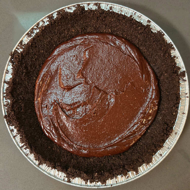 a photo of a mississippi mud pie before the brownie layer is baked. The brownie batter has been spread into the bottom of an oreo pie crust