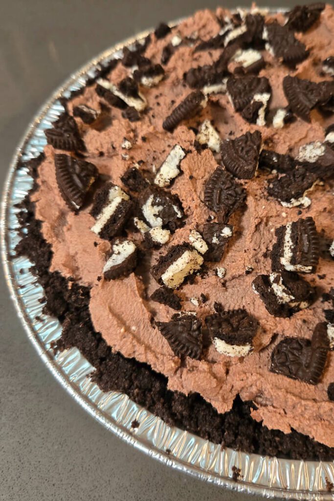 a close up photo of a Mississippi mud pie pictured with an Oreo crust topped with chocolate whipped cream and crushed Oreo cookies
