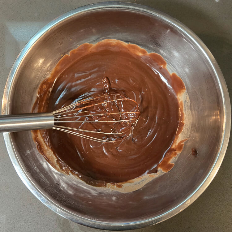 homemade chocolate pudding in a metal mixing bowl with a metal whisk