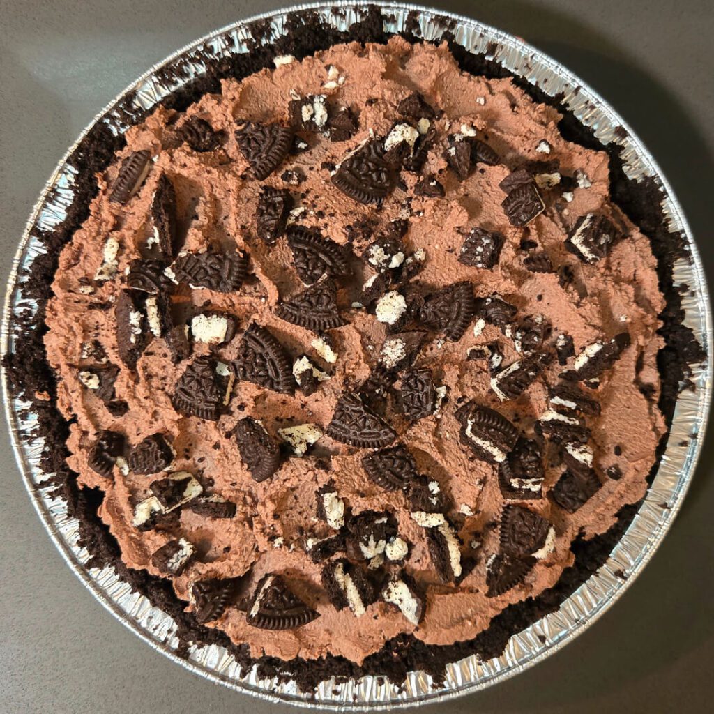 overhead photo of a Mississippi mud pie topped with crushed oreos and chocolate whipped cream