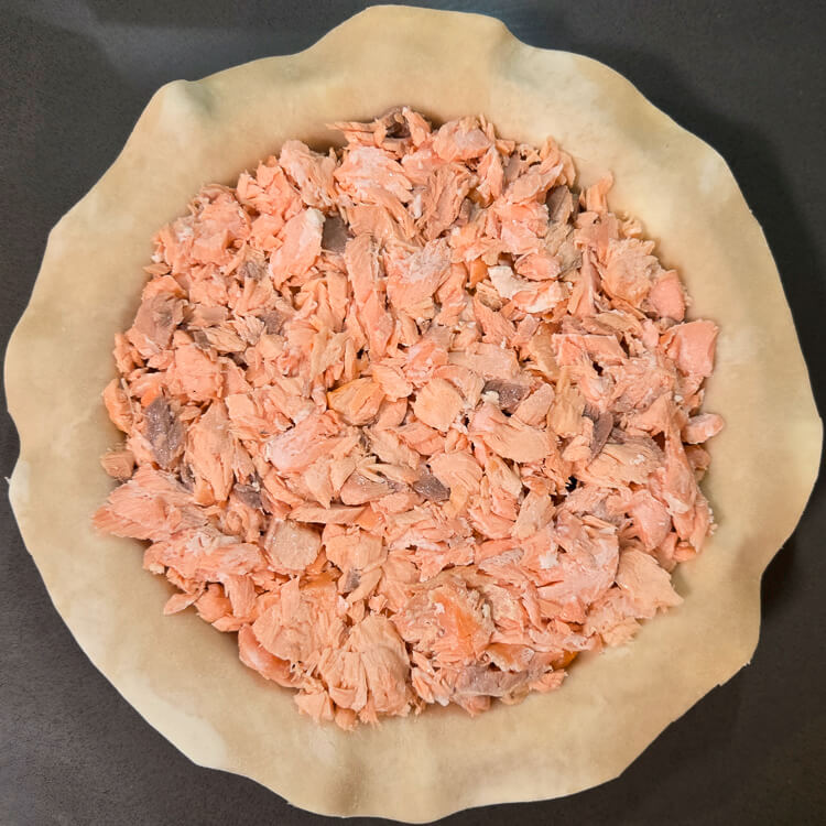 process photo of an Alaskan salmon pie being assembled after adding the salmon layer