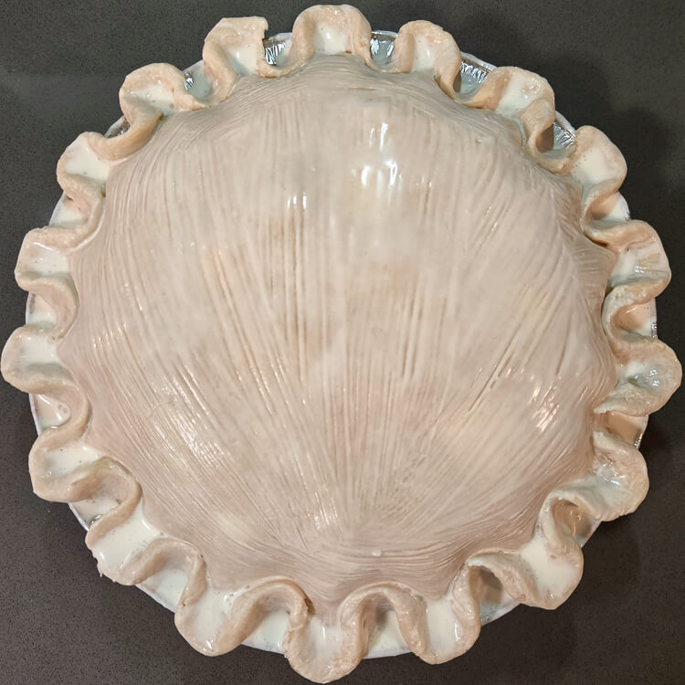 a double-crusted pie before the vents have been cut showing a cream wash and fluted edges
