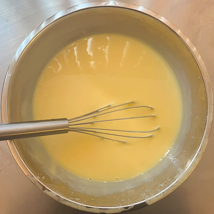 sour orange pie filling mixed in a metal mixing bowl with a metal whisk