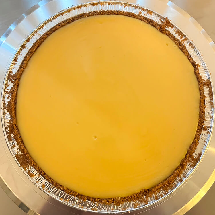 an overhead photo of a whole, baked sour orange pie. There is no topping and you can see a beautiful yellow-orange custard in a graham cracker crust