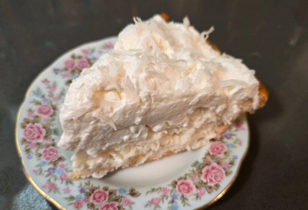 a close up photo of white christmas pie: a chiffon pie flavored with vanilla, almond, and coconut