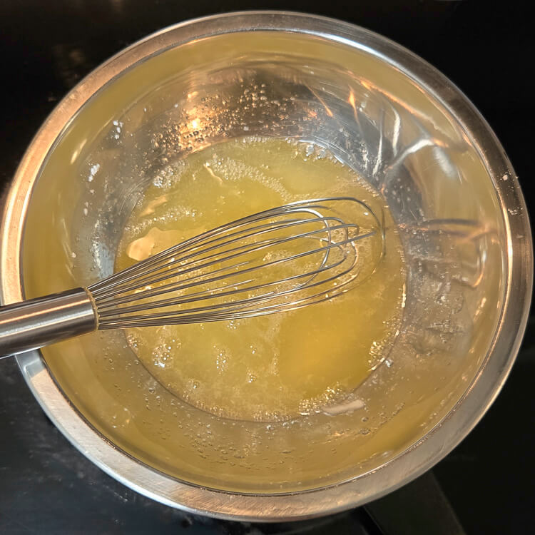 egg whites and sugar being whisked together on a double boiler
