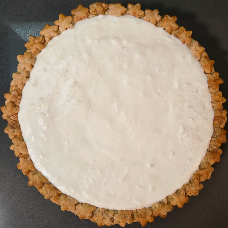 an overhead photo of a white christmas pie with a chiffon pie filling flavored with vanilla, almond, and coconut