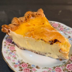 a close up photo of a slice of crème brûlée pie on an antique floral plate with a cracked golden caramel top
