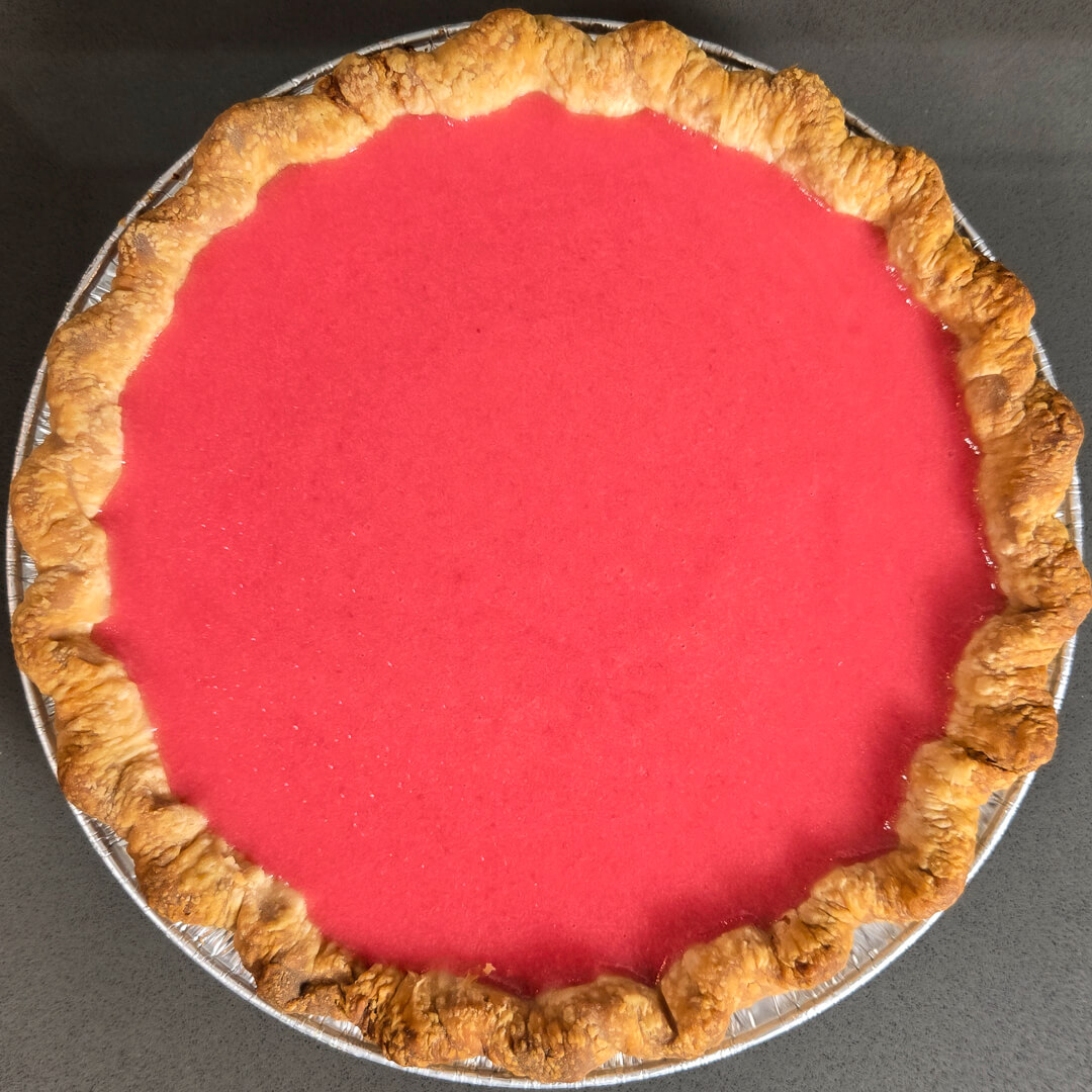 an overhead photo of cranberry curd set in a golden brown pie crust after the cranberry curd has set and chilled
