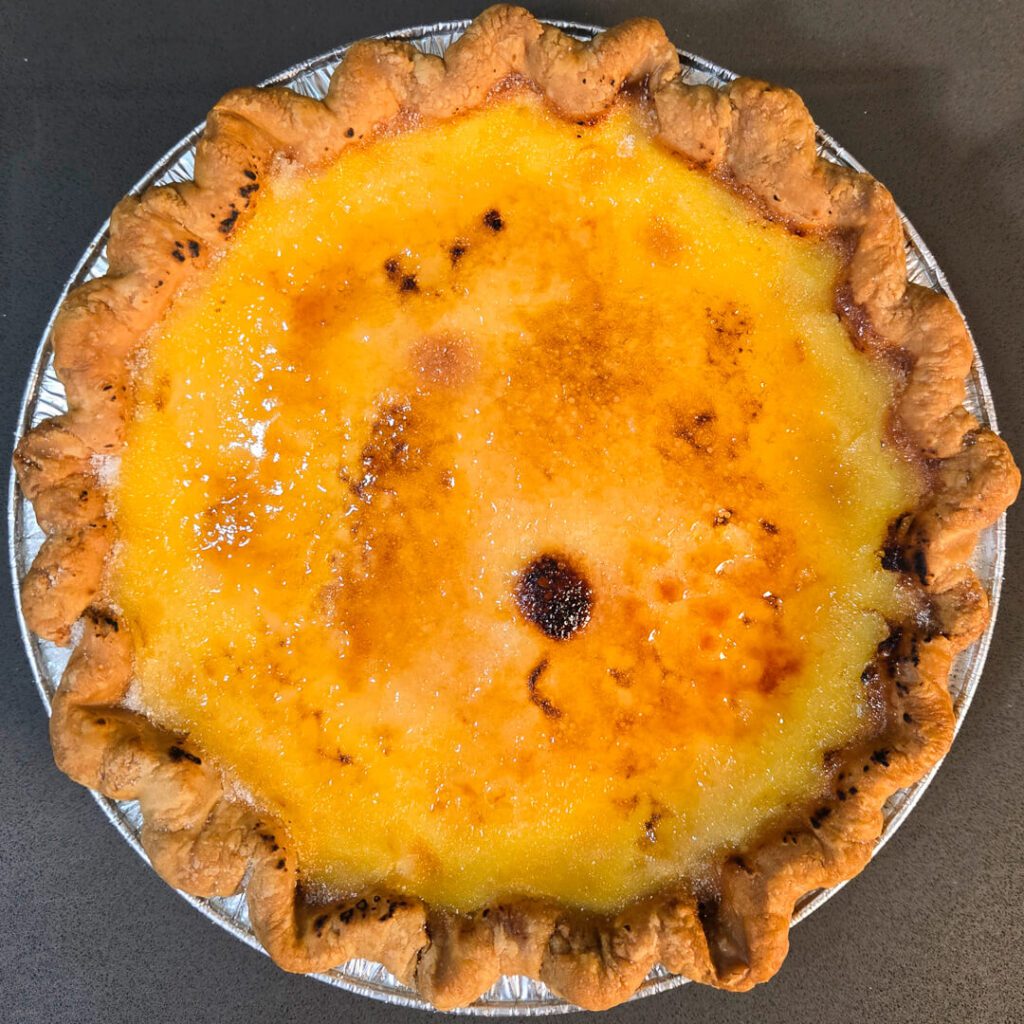 overhead photo of a crème brûlée pie showing a shiny, golden brown caramel topping