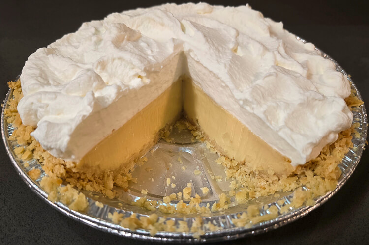 an atlantic beach pie with a slice cut out with a clear photo of the cross section: saltine cracker crust, citrus custard filling, and whipped cream topping